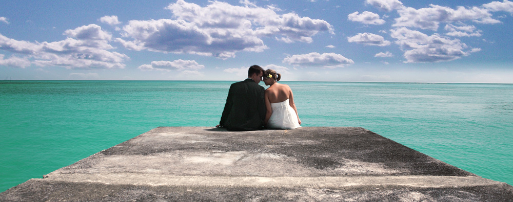 Jamaica Ocho Rios Wedding photo couple is sitting on the pier blu cloudy sky